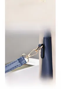 Detailed view of bicolor leather handbag with golden embossed text and premium metal clasp
