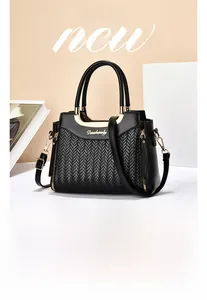 Detail of black woven handbag with gold hardware and adjustable shoulder strap
