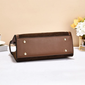 Detail of the handbag base with dark brown suede, caramel leather and gold metal feet