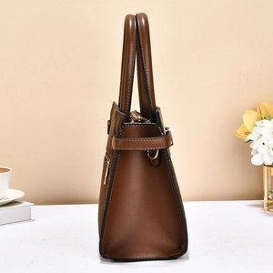Detail of a brown leather and suede tote bag showing the side strap and metallic D-ring