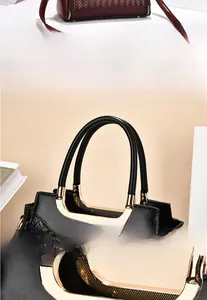 Detail of black woven handbag featuring unique golden circular metal handle and neat stitching
