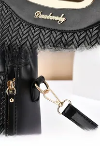 Macro view of woven black handbag detailing the golden Dunbaoly logo and hardware