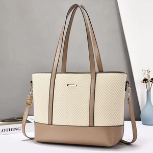 Macro detail of large tote bag showing herringbone straw weave and khaki faux leather textures