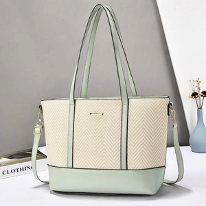Close-up of large tote bag with pale green leather and beige herringbone texture