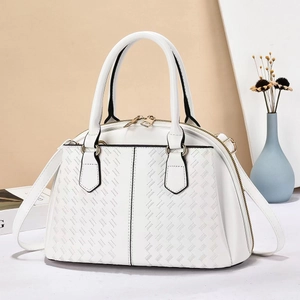 Detail of white dome handbag featuring woven texture and gold dual zippers