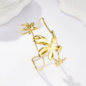 Dettaglio macro del bracciale aperto dorato con filo intrecciato e motivi floreali