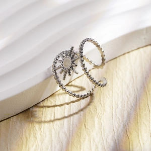 Minimalist silver starburst open ring on a textured white display stand
