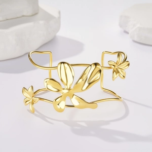 Dettaglio di un bracciale rigido dorato a forma di C con fiori 3D su pietre bianche lucide