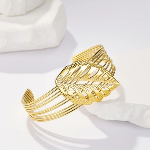 Dettaglio del design a foglia dorata su un ampio bracciale rigido a C in acciaio inossidabile