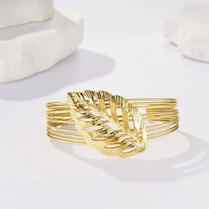 Dettaglio macro del bracciale a più strati in filo dorato con foglia traforata su pietre