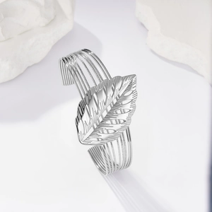 Dettaglio di foglia monstera traforata su un bracciale rigido d'argento a più linee