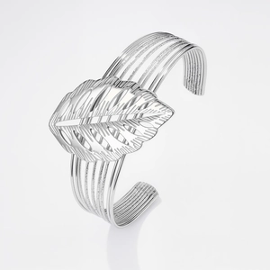 Dettaglio ravvicinato di un bracciale a fascia argento con motivo a foglia e venature