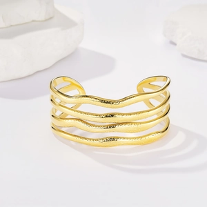 Bracciale rigido a strati ondulati dorati con finitura martellata e superfici lucide