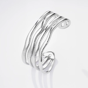 Dettaglio del bracciale rigido argento con linee ondulate e finitura texture lavica