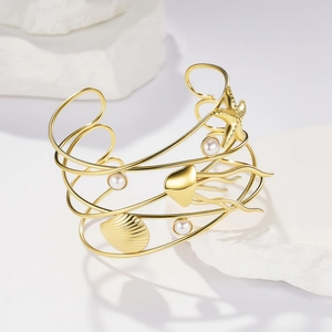 Bracciale rigido dorato con stelle marine conchiglie e perle su base di pietra bianca