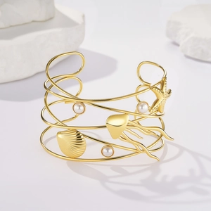 Dettaglio del bracciale rigido dorato con stelle marine, conchiglie e perle bianche