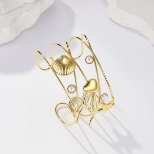 Bracciale rigido dorato a tema oceano con stella marina, medusa, conchiglia e perle