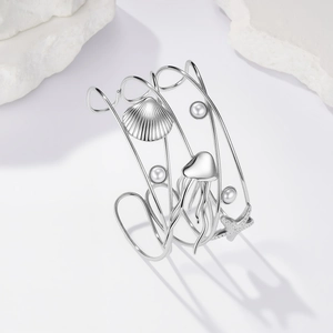 Dettaglio del bracciale rigido argento con elementi di conchiglie, meduse e perle