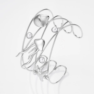 Dettaglio del bracciale rigido argento intrecciato con stelle marine e perle lucide
