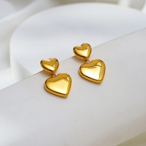 Elegante goldene Herzohrringe aus poliertem Edelstahl auf weißem Displayständer