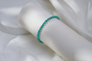 Détail macro des perles turquoise et des sphères dorées sur un bracelet perlé