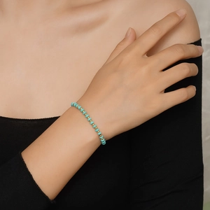 Détail du bracelet en perles de turquoise et accents dorés porté par un mannequin