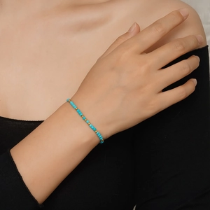 Vue détaillée d'un bracelet de perles bleu turquoise avec billes dorées au poignet
