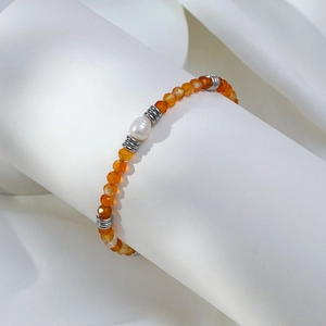 Détail d'un bracelet en cornaline orange avec une perle sur un support blanc pur