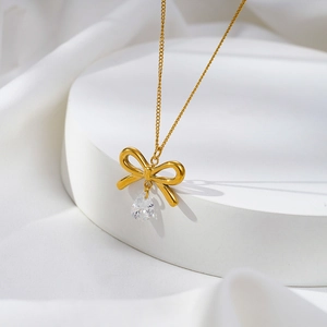 Minimalist bow pendant necklace with teardrop zircon on a white display stand