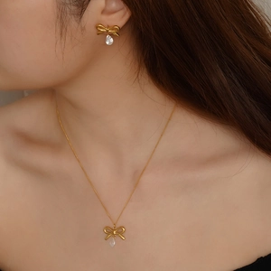 Elegant gold bow jewelry set with crystal teardrop pendants on necklace and earrings