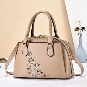 Detail of khaki leather handbag featuring exquisite floral embroidery and golden hardware