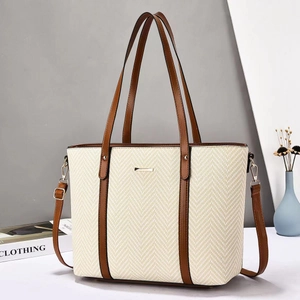 Detail of herringbone woven texture and brown leather trim on a beige tote bag