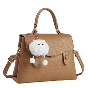 Brown lychee leather tote bag with top handle, crossbody strap, and monster charm detail