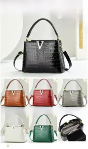 Detail view of crocodile embossed bag featuring internal compartments and V-shaped buckle