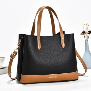 Classic black pebbled leather tote bag with brown handles and adjustable shoulder strap