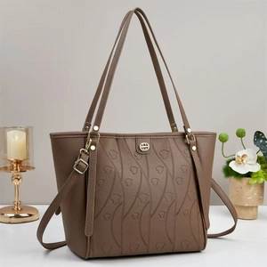 Sac cabas marron foncé avec gaufrage cœur et finitions dorées sur bureau blanc