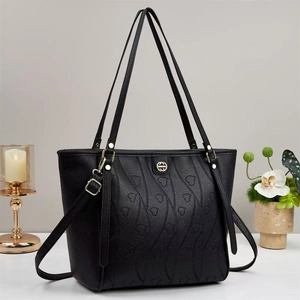 Détails d'un sac cabas en cuir noir avec gaufrage coeur et accessoires dorés