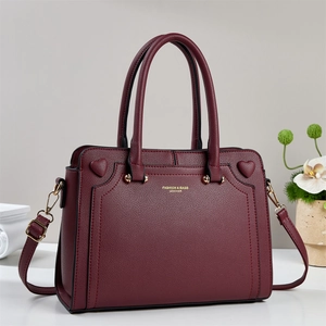 Deep red lychee textured leather handbag with gold hardware and heart embossed details
