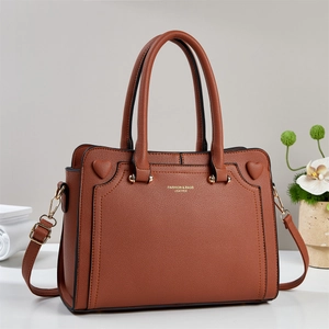 Detailed macro of brown pebble leather handbag featuring heart accents and gold lettering