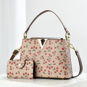 Beige bucket bag and wallet set with red cherry print and gold V metal hardware