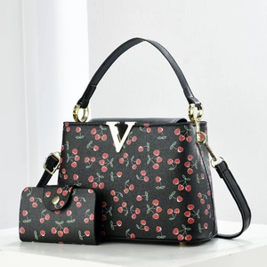 Close-up of black cherry print bucket bag and matching wallet with gold V logo