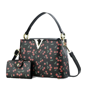 Luxe black bucket bag with cherry print, pebbled leather texture, and golden V-shaped hardware