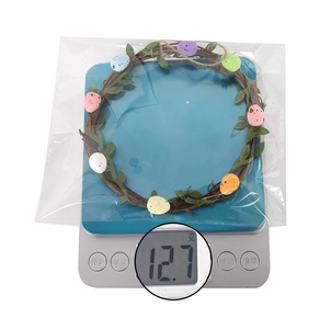 Easter wreath with pastel eggs and green leaves being weighed on a digital scale
