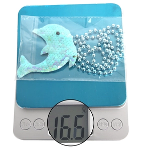 Delfin-Anhänger mit blauen Pailletten an einer Perlenkette, wiegt 16,6 g auf einer Digitalwaage