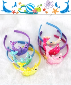 Flat lay of colorful sequined dolphin headbands on white plush fabric for kids party