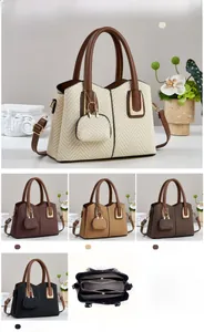 Detail view of woven texture tote bag with mini charm pouch and multi-compartment interior