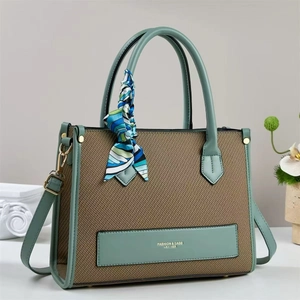 Detail of woven brown tote bag with light green leather trim and decorative silk scarf