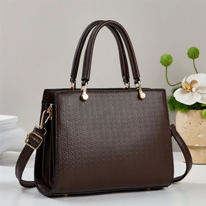 Detail of dark brown leather handbag featuring geometric embossed texture and golden buckle