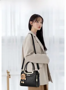 Détail du sac à main en cuir PU noir tissé avec logo doré et pompon en fourrure marron