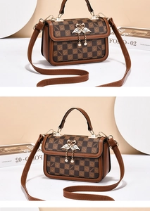 Detail of checkered square bag with golden swan clasp and decorative pearl fringe